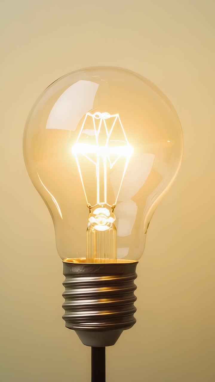 Video verticale: lampadina in vetro trasparente che si illumina in studio mostrando il filamento e la base in metallo