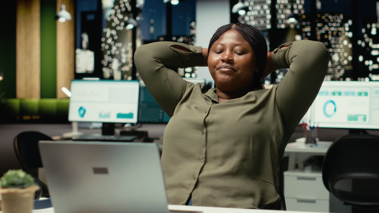 Black company worker reclining in a chair and relaxing at midnight