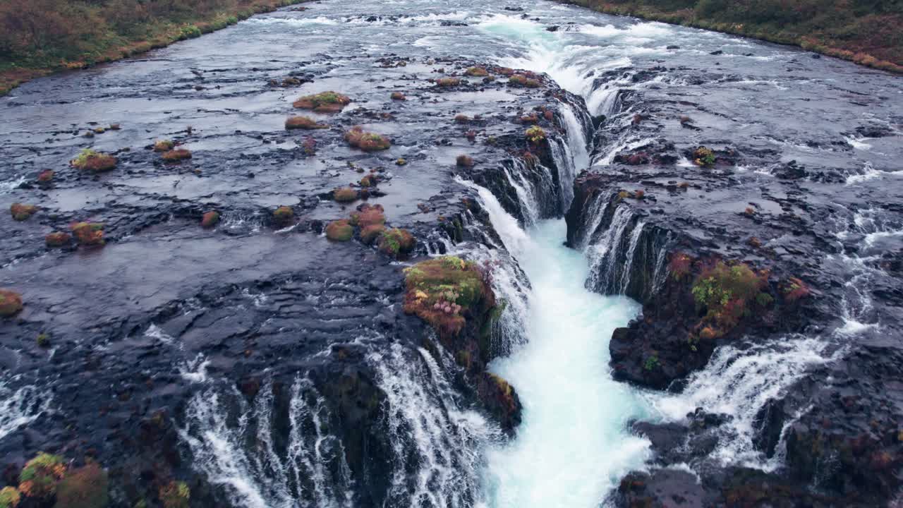 aerial: paso aéreo inverso de bruarfoss cascada de agua en el sur de islandia que es muy pintoresco con la hermosa cascada azul de cae en la piscina de inmersión debajo