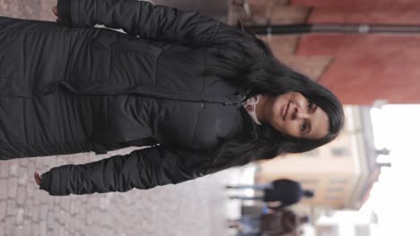 Vertical---Female-Tourist-Turn-Around-And-Smiles-To-Camera-While-Strolling-Through-Charming-Street-Of-Stockholm-In-Sweden