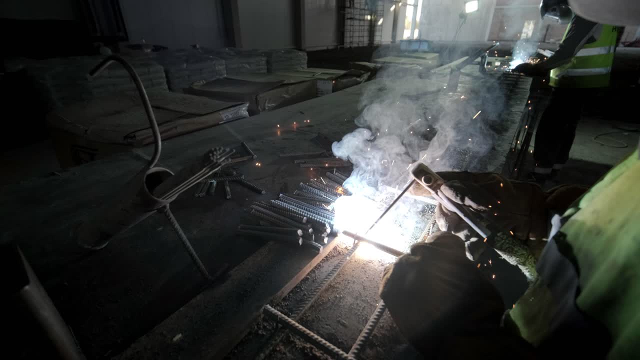 Professional welders are working in the factory wearing safety equipment. Metalwork manufacturing, industrial process.