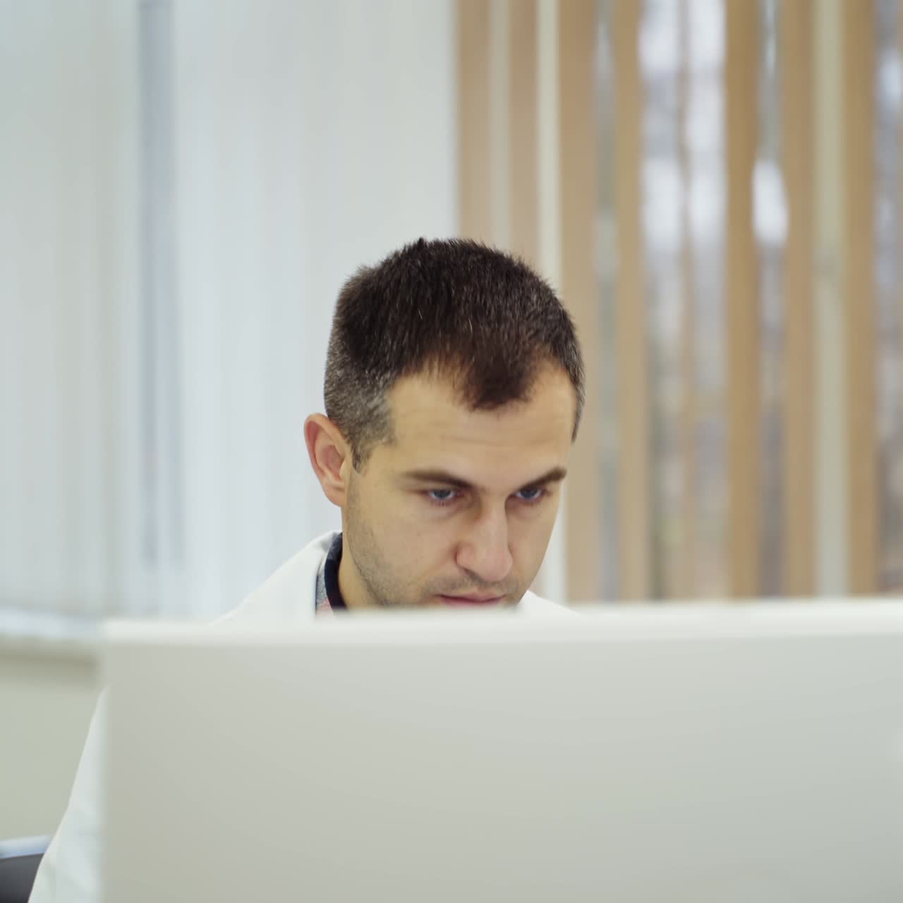 Confident doctor sitting at his desk with computer. Doctor in his office