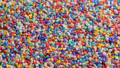 crushed colored stones on flat surface, slowly spinning, loopable closeup