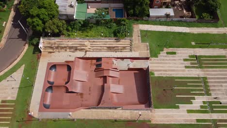 Drone-wide-look-down-fly-by-of-empty-skate-park-and-surrounding-park