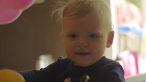 a baby girl in a crib playing with balloons