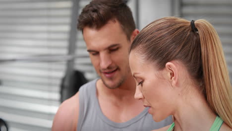 trainer watching client lift dumbbells at crossfit gym