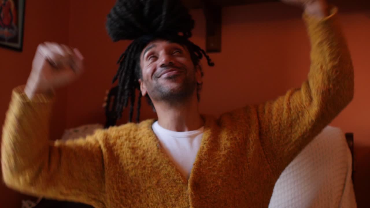 Happy man cheering, lifting hands on his sofa