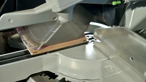 close-up of a man's hand working on a machine with a circular saw