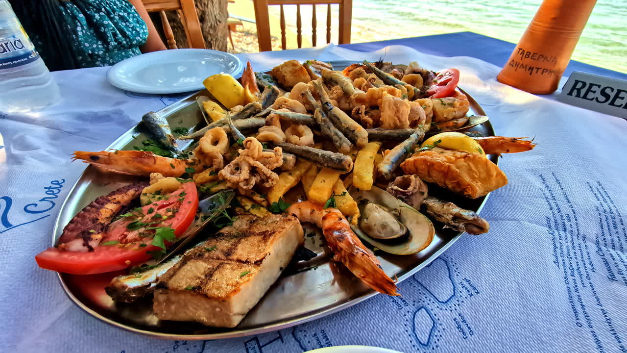 Grilled Seafood Platter Served At Greek Beach Restaurant With Sea Views In Crete, Greece. closeup pullback shot