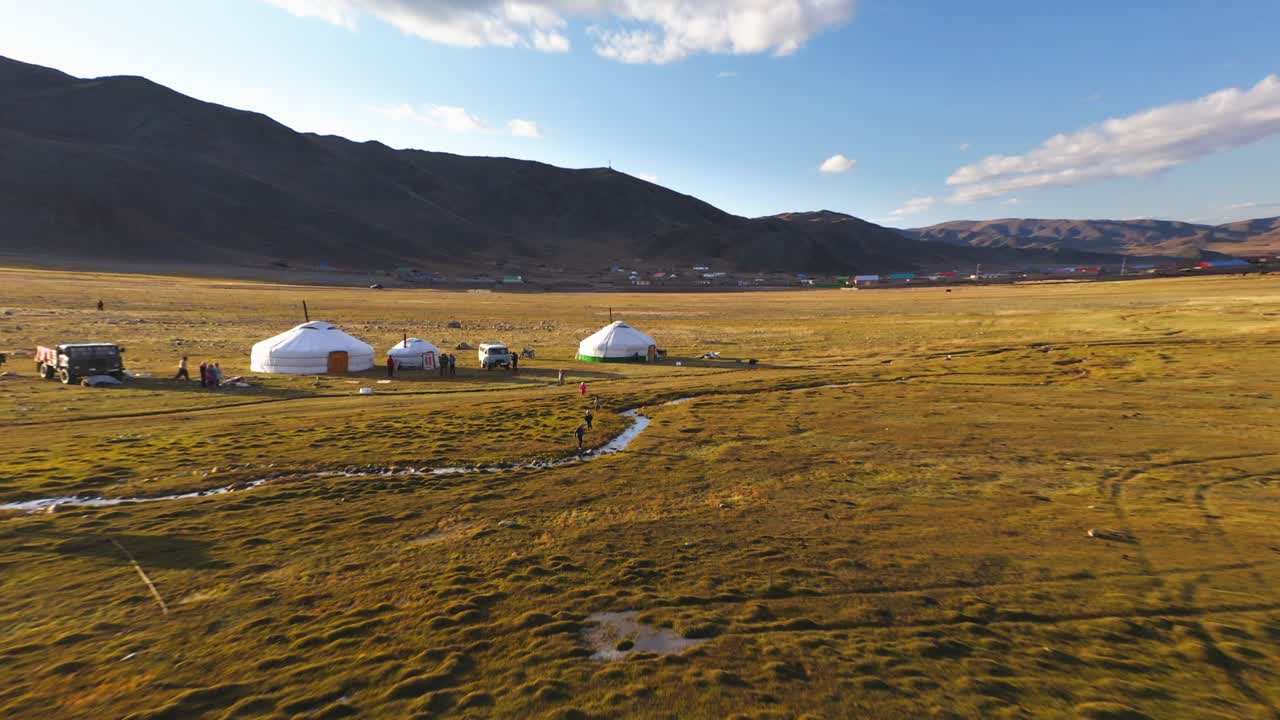 Nomadic Mongolian children playing outside ger tents in Altai Mountains, aerial reveal