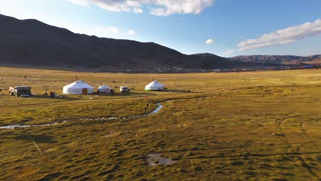 nomadic mongolian children playing outside ger tents in altai mountains, aerial reveal
