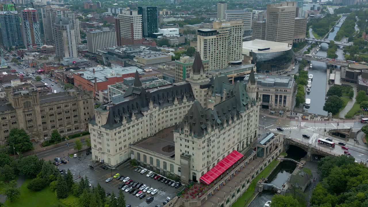 Fairmont Château Laurier: vista aerea SW con drone dell'iconico punto di riferimento a Ottawa, distinto per il suo stile architettonico rinascimentale francese, con autobus turistici che passano accanto alla struttura, in un loop video continuo