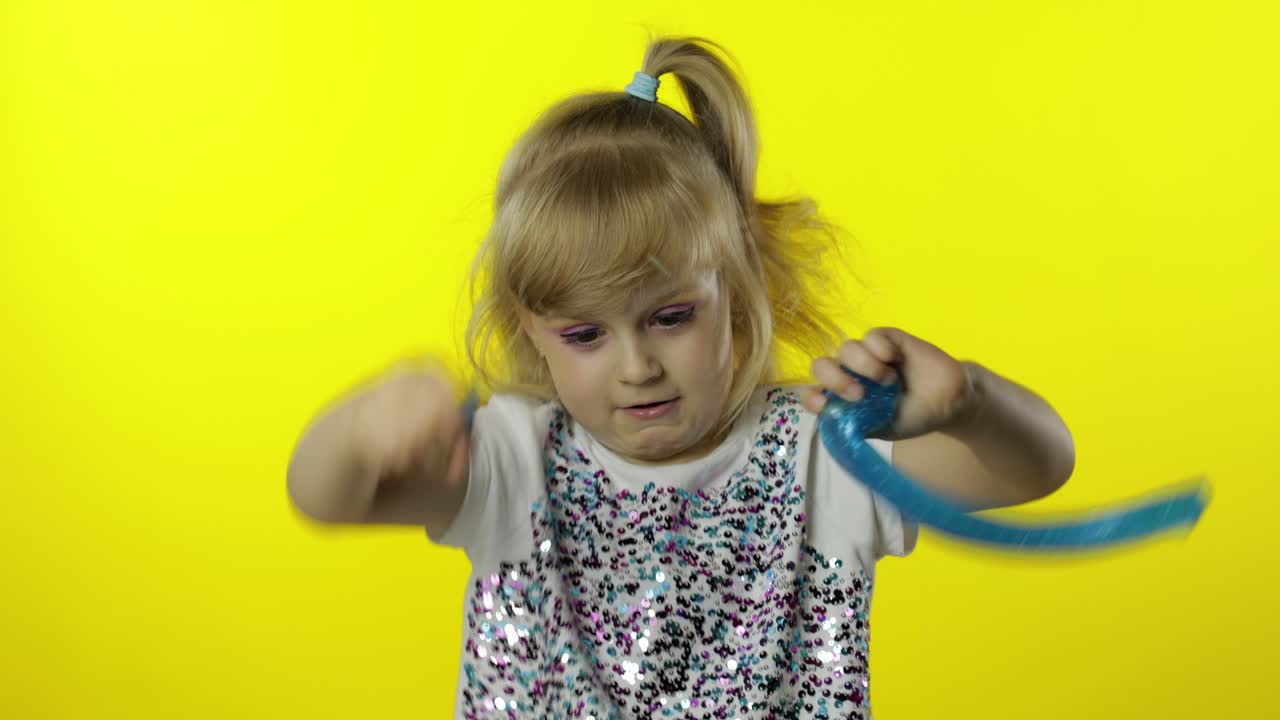Kid playing with hand made toy slime. Child having fun making turquoise slime. Funny pupil girl