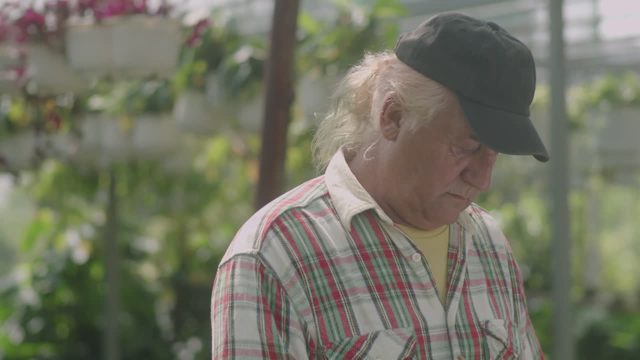 Senior Nurseryman Taking Notes at Work in Greenhouse