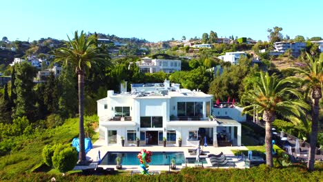 drone flying towards luxurious mansions on hollywood hills in los angeles