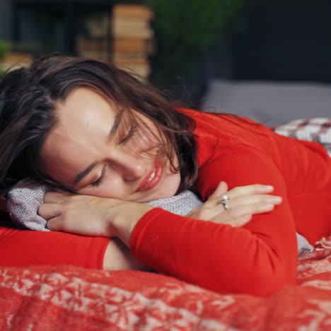 happy girl on bed at christmas. young woman on bed resting at home with pillow at new year time. joyful mood of a pretty female at christmas.