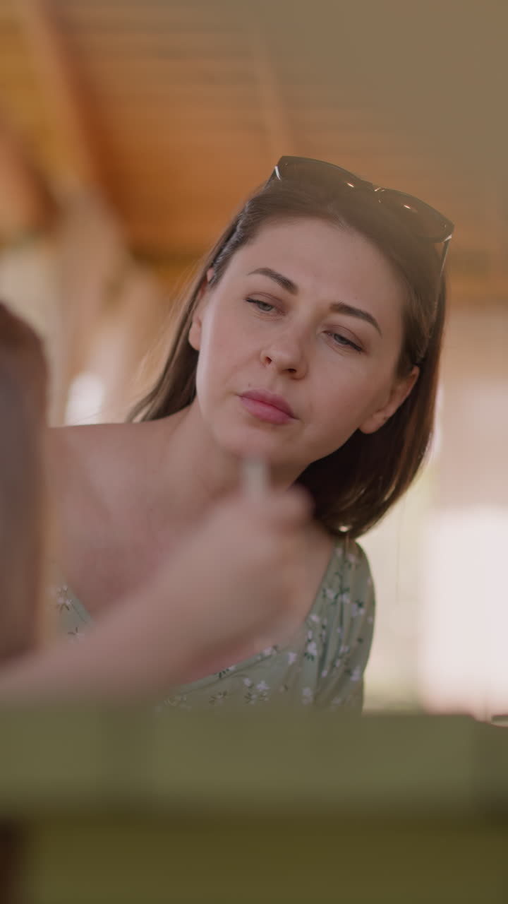 Careful mother wipes little girl face at lunch in hotel restaurant closeup slow motion. Woman cleans daughter face. Family on resort cafe terrace