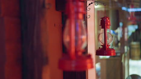 close-up view of two vintage red lanterns hanging on wooden beams with a warm, rustic background