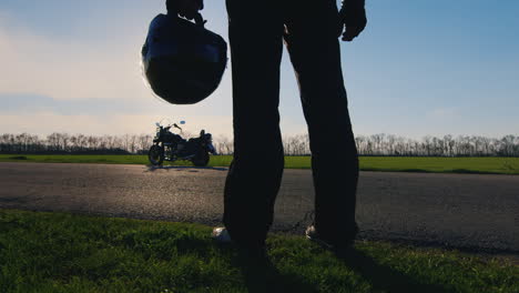 Motociclista-Sosteniendo-Un-Casco-En-Una-Motocicleta-Y-Mira-Al-Sol