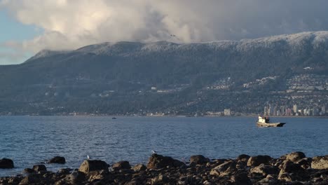 tug boat floating in the calm sea with mountains in the background