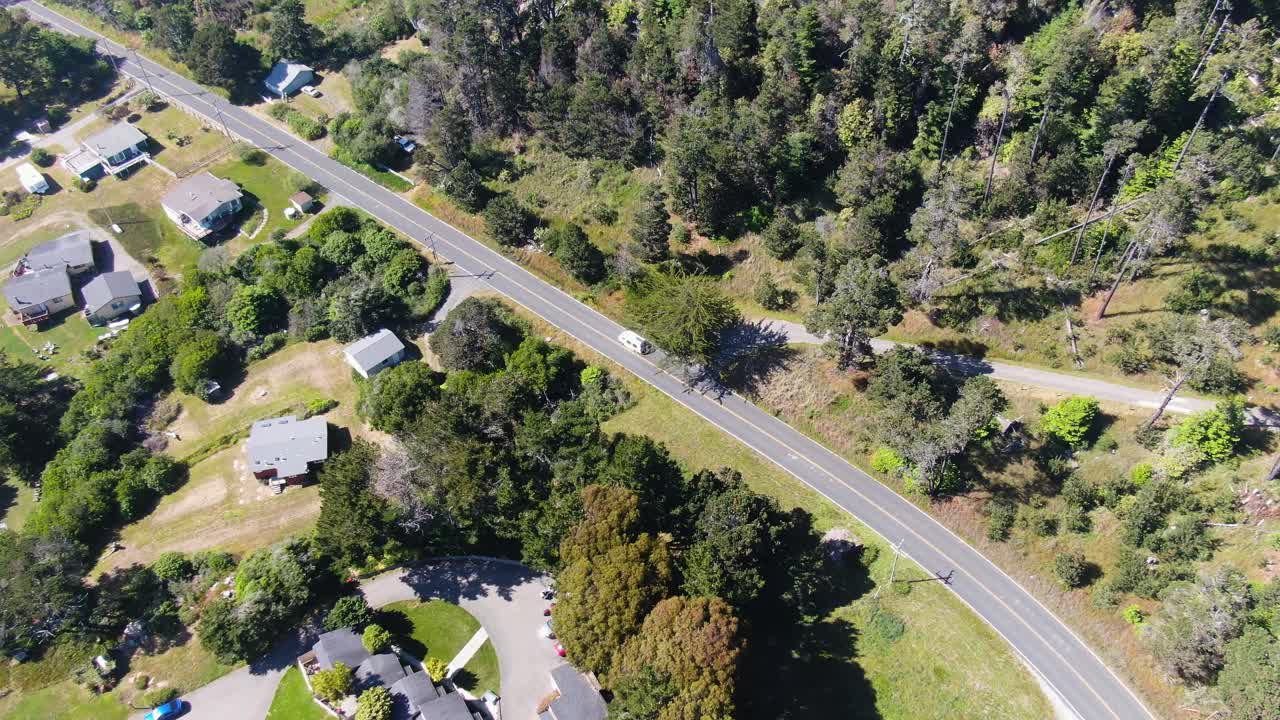 tomada aérea capturando una vista panorámica de los barrios rurales rodeados de vegetación, y un camino a un lado viajado por automóviles en la bahía de bodega y la costa de gualala, california