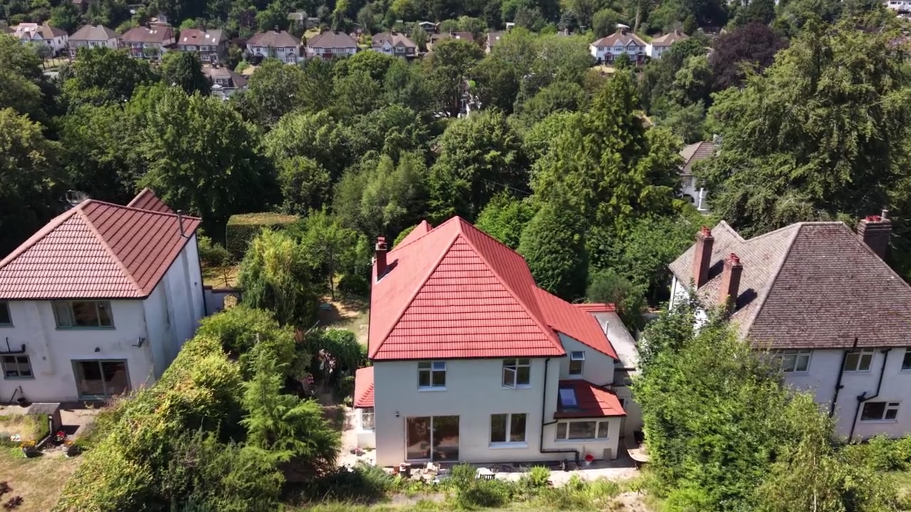 Nyrenoveret parcelhus i en beboelsesforstad i Croydon, London, England, omgivet af velplejede haver og nabohuse, luftoptagelse med fremadgående dolly-bevægelse, der afslører