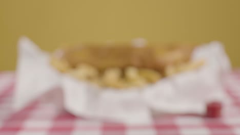 person eating traditional british takeaway meal of fish and chips holding wooden fork with smiling face