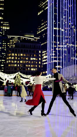 couple ice skating at night in a festive city rink