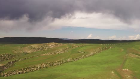 mountain peaks and grassland are under white clouds.