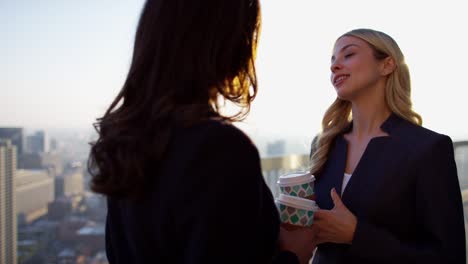 multi ethnic business females drinking coffee on rooftop
