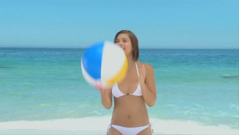 attractive brownhaired woman playing with a beach ball