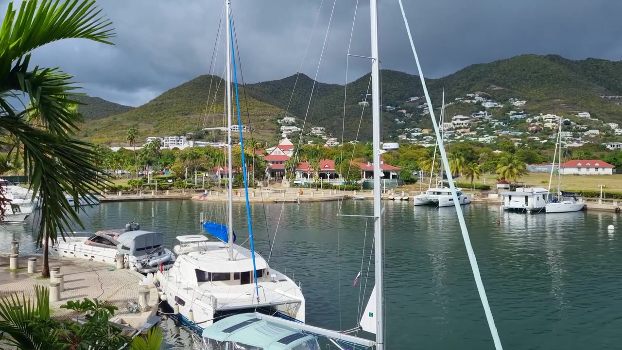 Catamarani ancorati riposano a Simpson Bay, Sint Maarten, mentre nuvole temporalesche scure si addensano sopra la costa collinare durante la stagione degli uragani, catturando l'atmosfera drammatica del clima tropicale caraibico