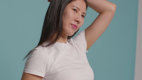 푸른 스튜디오 배경 앞의 젊은 여성이 사진 부스 스타일의 초상화를 위해 포즈를 취하고 있습니다.