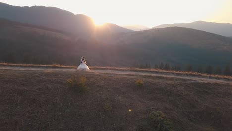 bride and groom pose on mountain top at sunset