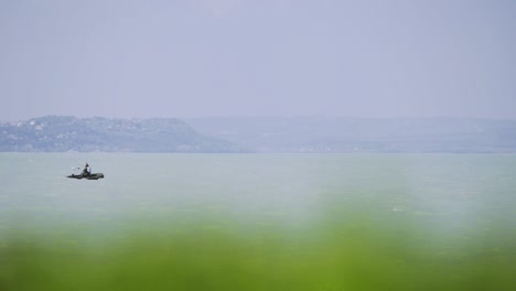 Imágenes-Del-Paisaje-De-La-Tarde-Con-Un-Pequeño-Bote-Que-Se-Mueve-Horizontalmente-Cerca-De-La-Orilla-De-Zamárdi,-Lago-Balaton