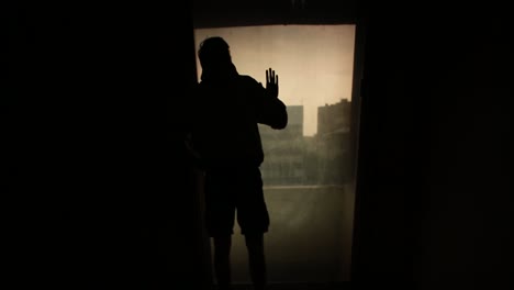 person looking out of a window on a stormy day