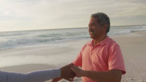 Glückliches-Hispanisches-Seniorenpaar,-Das-Bei-Sonnenuntergang-Am-Strand-Tanzt