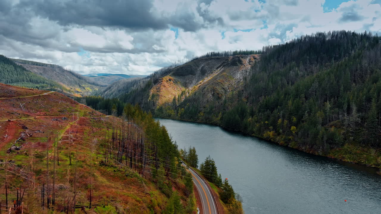 Catching up with the car riding by the highway over the mountain river. Rocky landscape of Oregon State, the USA on cloudy day. Aerial view.