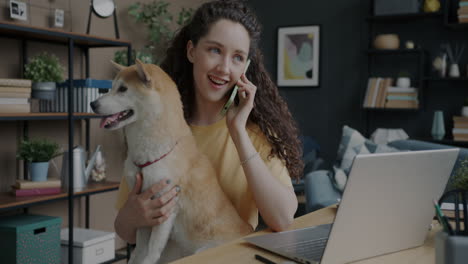 woman talking on phone while holding a dog at home office