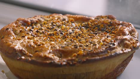 whole view of delicious gourmet chicken and mushroom pie with seeds on top with rustic texture of pastry ready to portion and serve for dinner