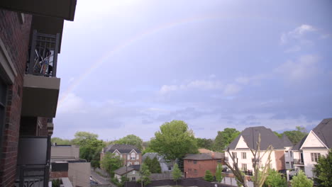 a rainbow appears over a neighbourhood after a storm