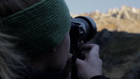 close up of woman taking pictures of beautiful mountain landscape in the morning -rear view in slow motion