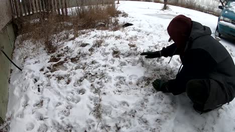 man trying to dig out a big rock from the ground during the winter