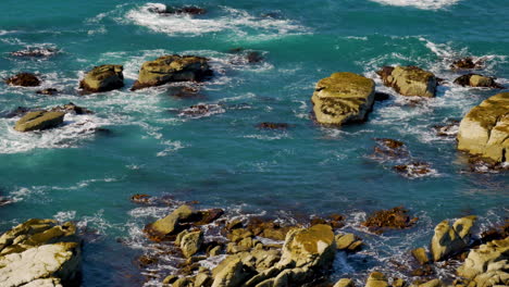 tiro em câmera lenta de ondas do oceano pacífico batendo contra rochas pendentes durante a luz do verão