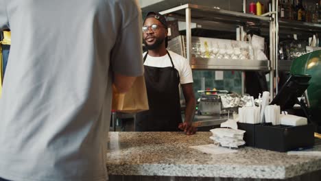 A-Black-person-in-glasses-gives-an-order-to-a-food-delivery-man-in-a-doner-market-and-shows-a-sign-of-approval.-Video-filmed-in-high-quality