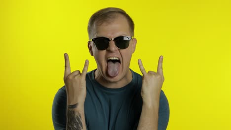 man posing in t-shirt. crazy guy shouts, celebrates, wins, shows tongue, makes horns symbol