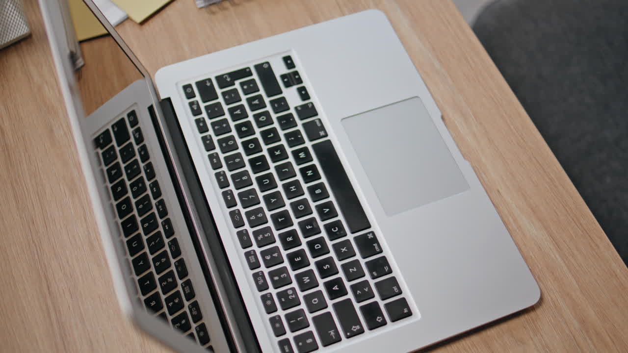 Modern computer standing desk closeup. Grey laptop at office wooden workplace