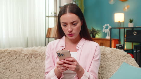 Young woman angrily texting on smartphone waving hand frustrated by chat messages and visible dismay