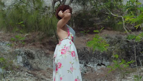 low angle of a red hair curly latina standing at rock cliff in a tropical caribbean park on a sunny day