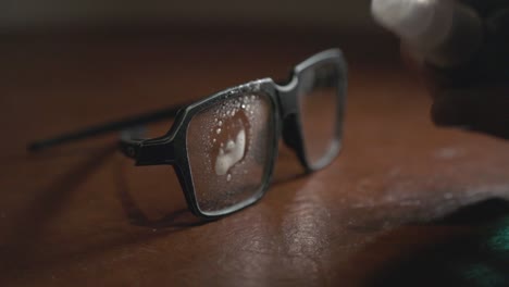 Cleaning-The-Square-Shaped-Sunglasses-Placed-On-The-Wooden-Table